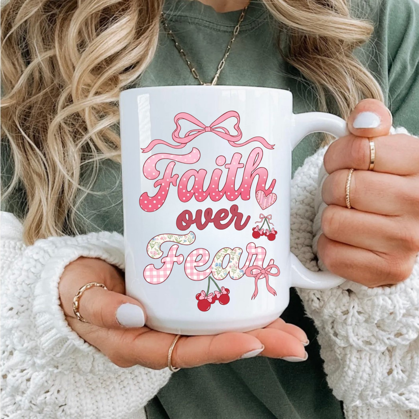 Person holding a white mug with 'Faith over Fear' design