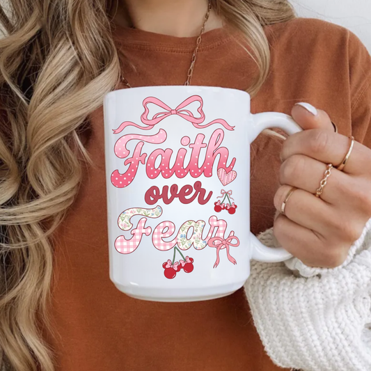 Person holding a mug with 'Faith over Fear' text and decorative elements.