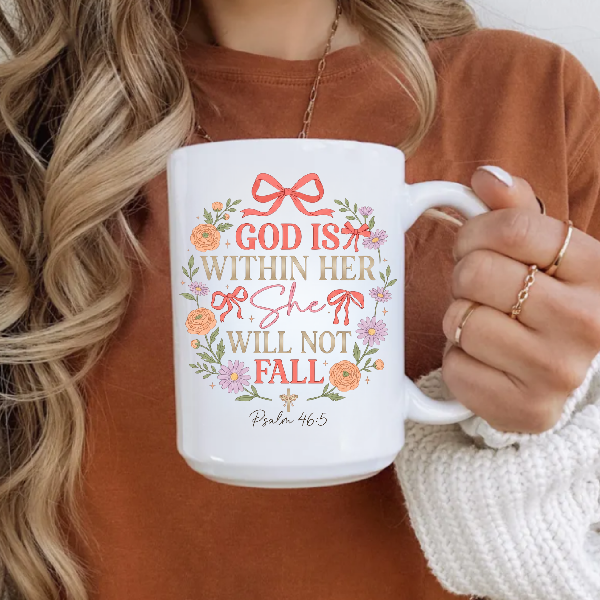 Person holding a mug with decorative text 'God is within her, she will not fall' and design