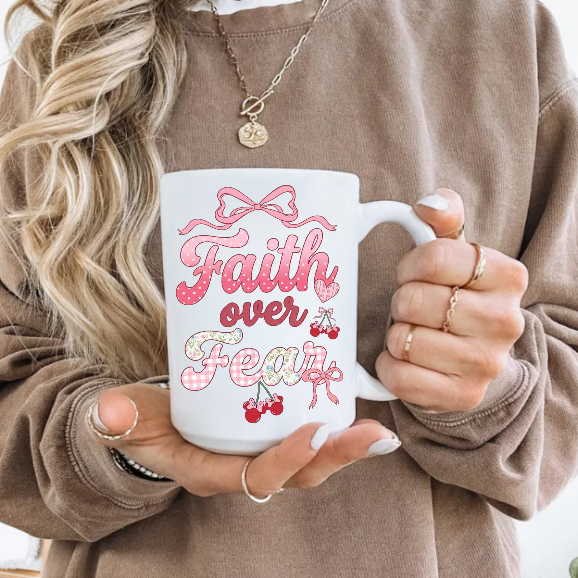 Person holding a white mug with 'Faith over Fear' text in pink and red.