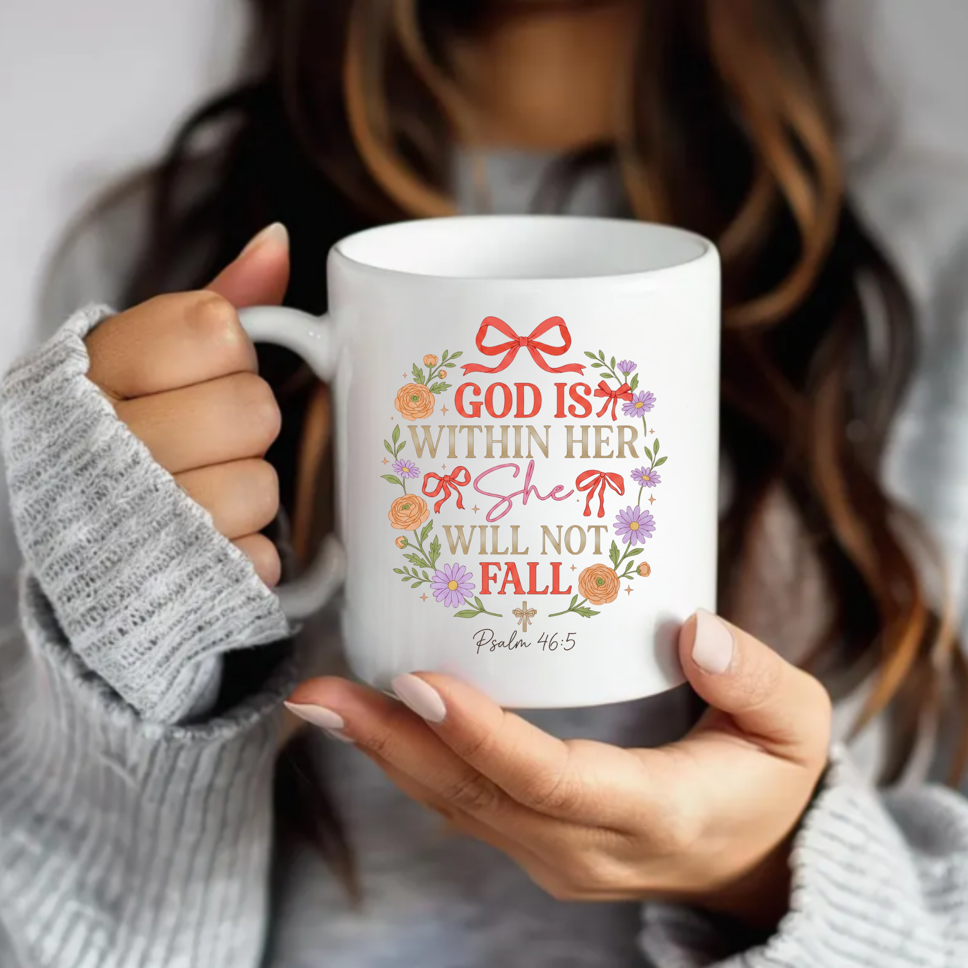 Person holding a mug with decorative text 'God is within her, she will not fall' and floral design