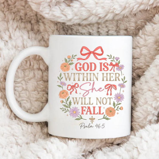 White mug with decorative text 'God is within her, she will not fall' and floral design on a soft, beige surface