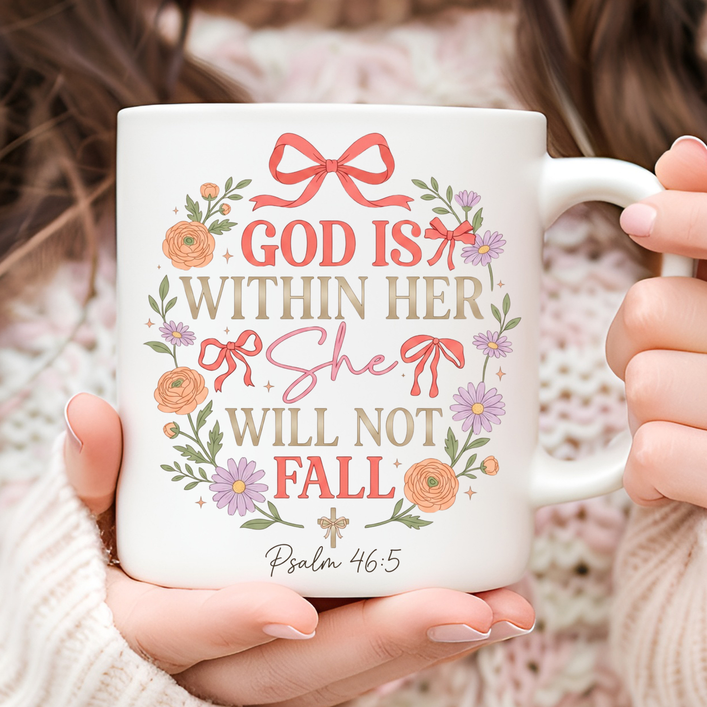 White mug with decorative text 'God is within her, she will not fall' and flowers held by a person