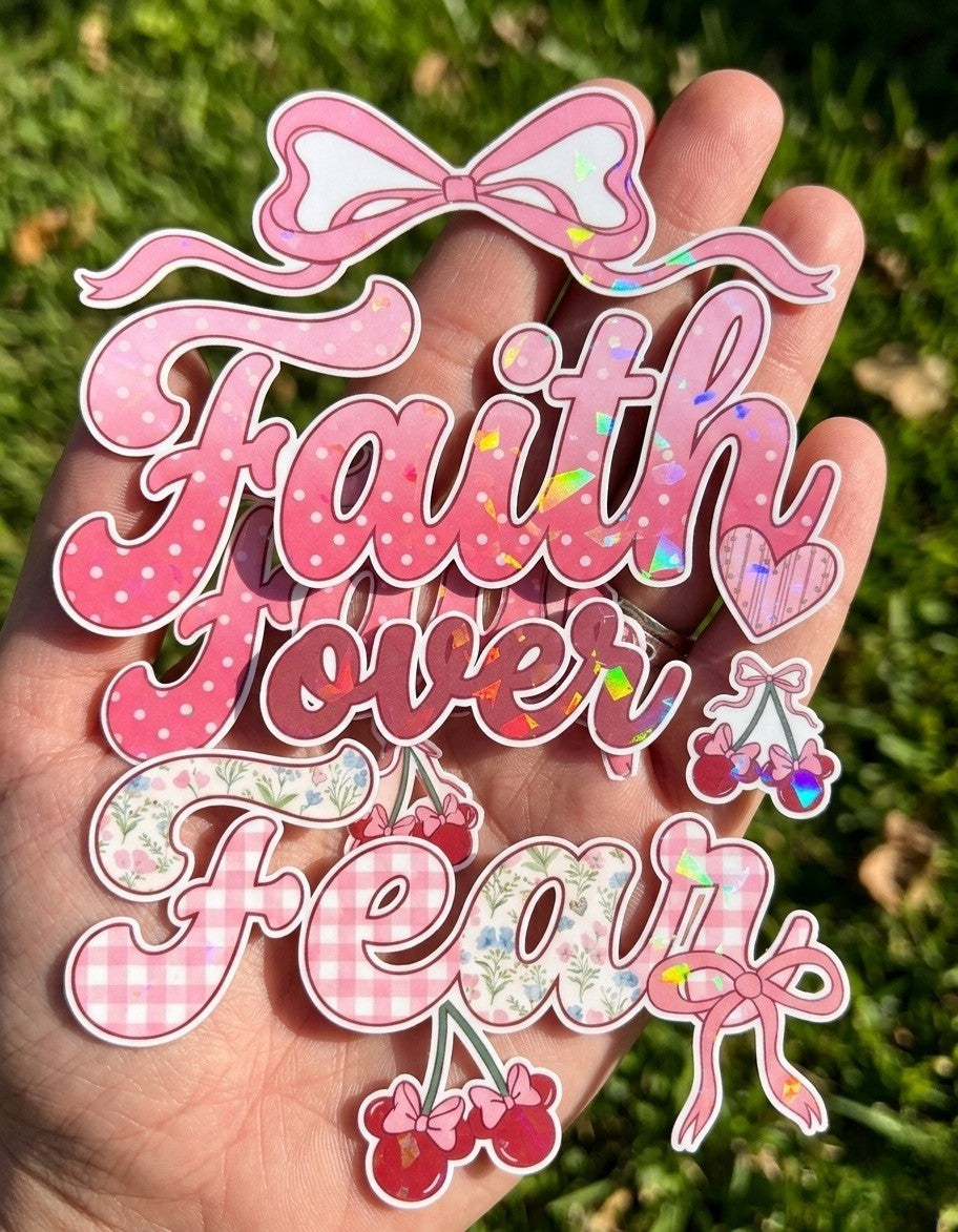 Decorative sticker with 'Faith over Fear' sticker held in a hand against a grass background