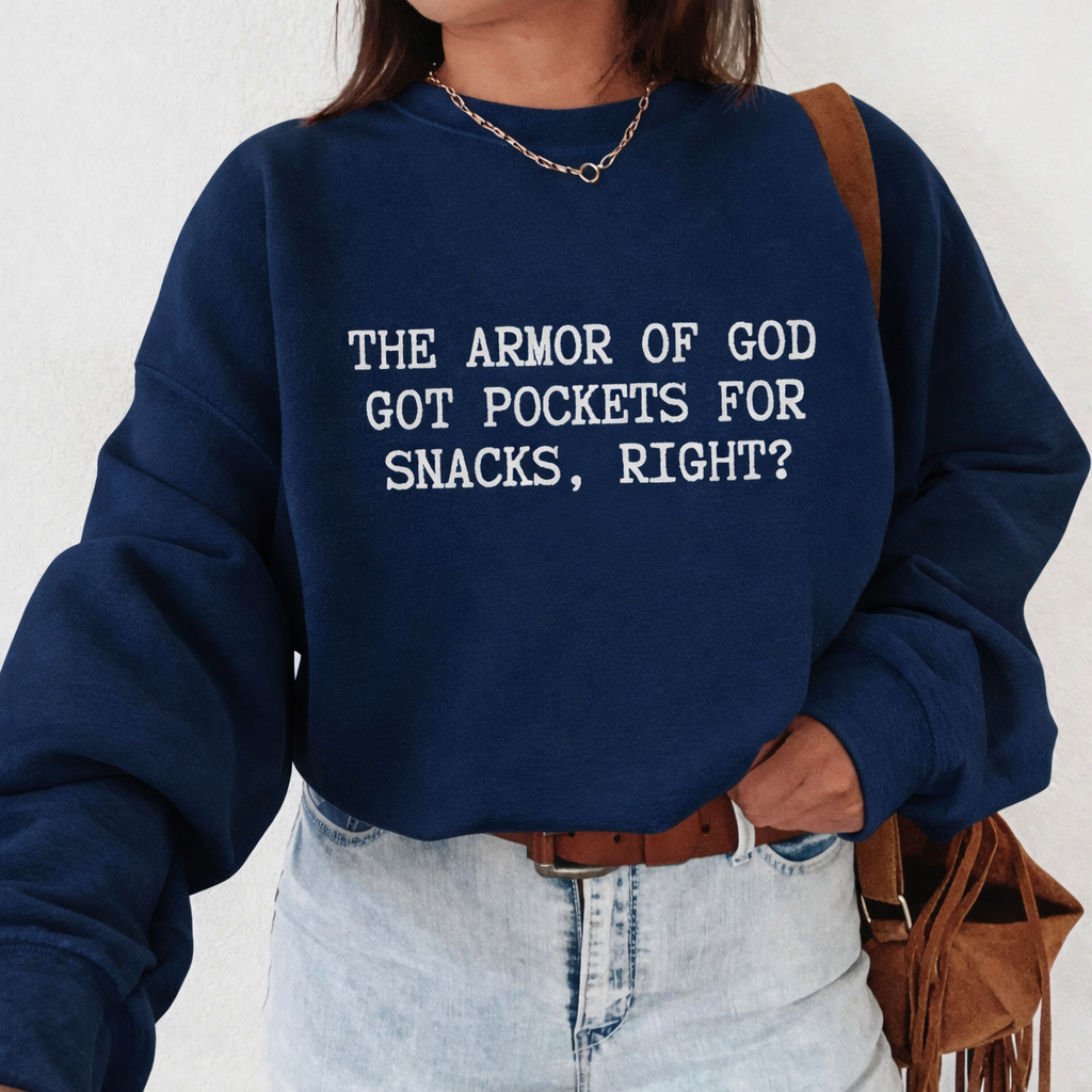 Person wearing a navy blue sweatshirt with humorous text 'The Armor of God got pockets for snacks, right?', standing against a plain background.