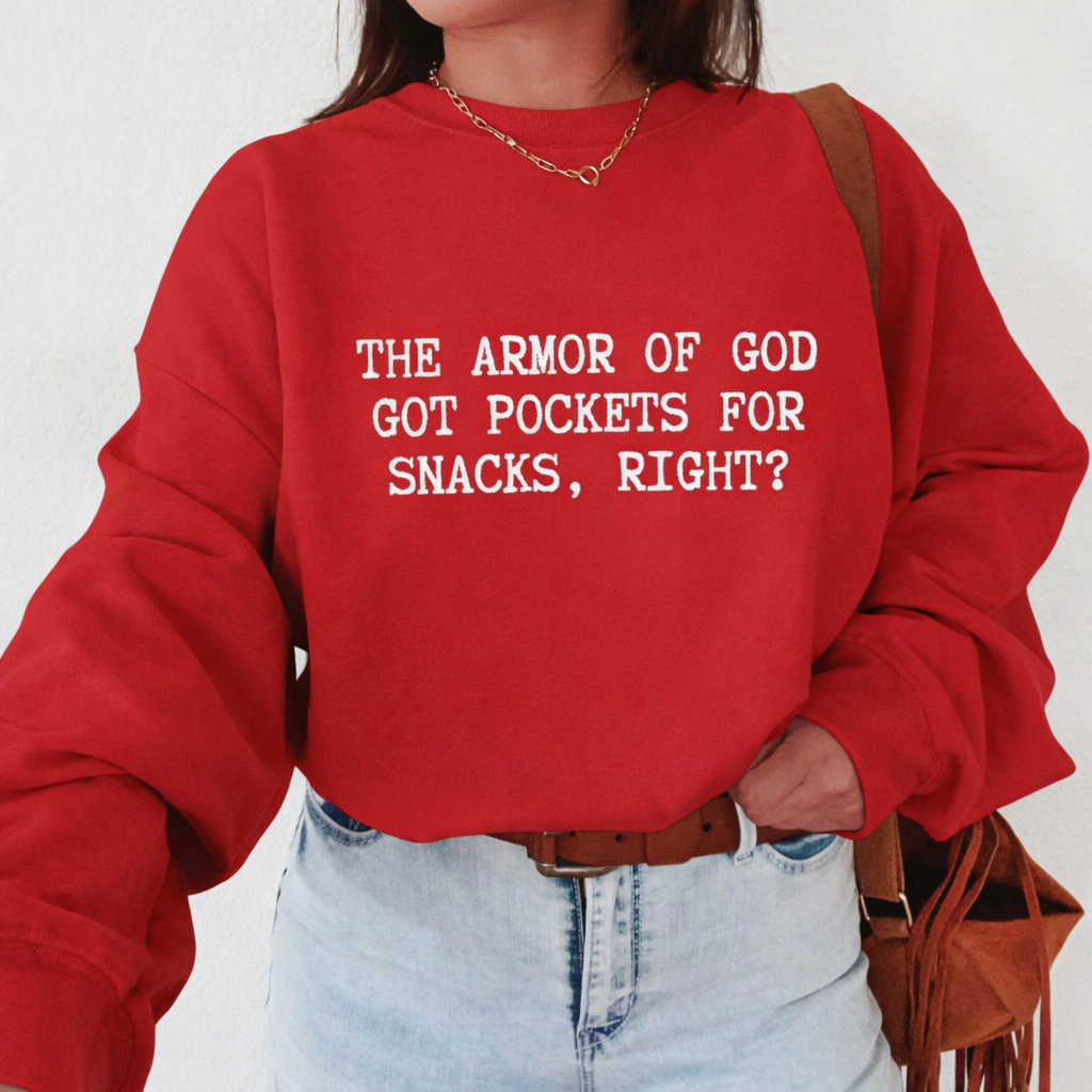 Person wearing a red sweatshirt with text 'The Armor of God got pockets for snacks, right?', standing against a white background