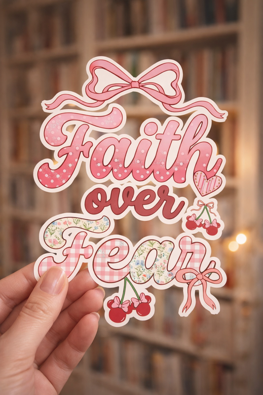 Sticker with 'Faith over Fear' text held in front of a blurred bookshelf background