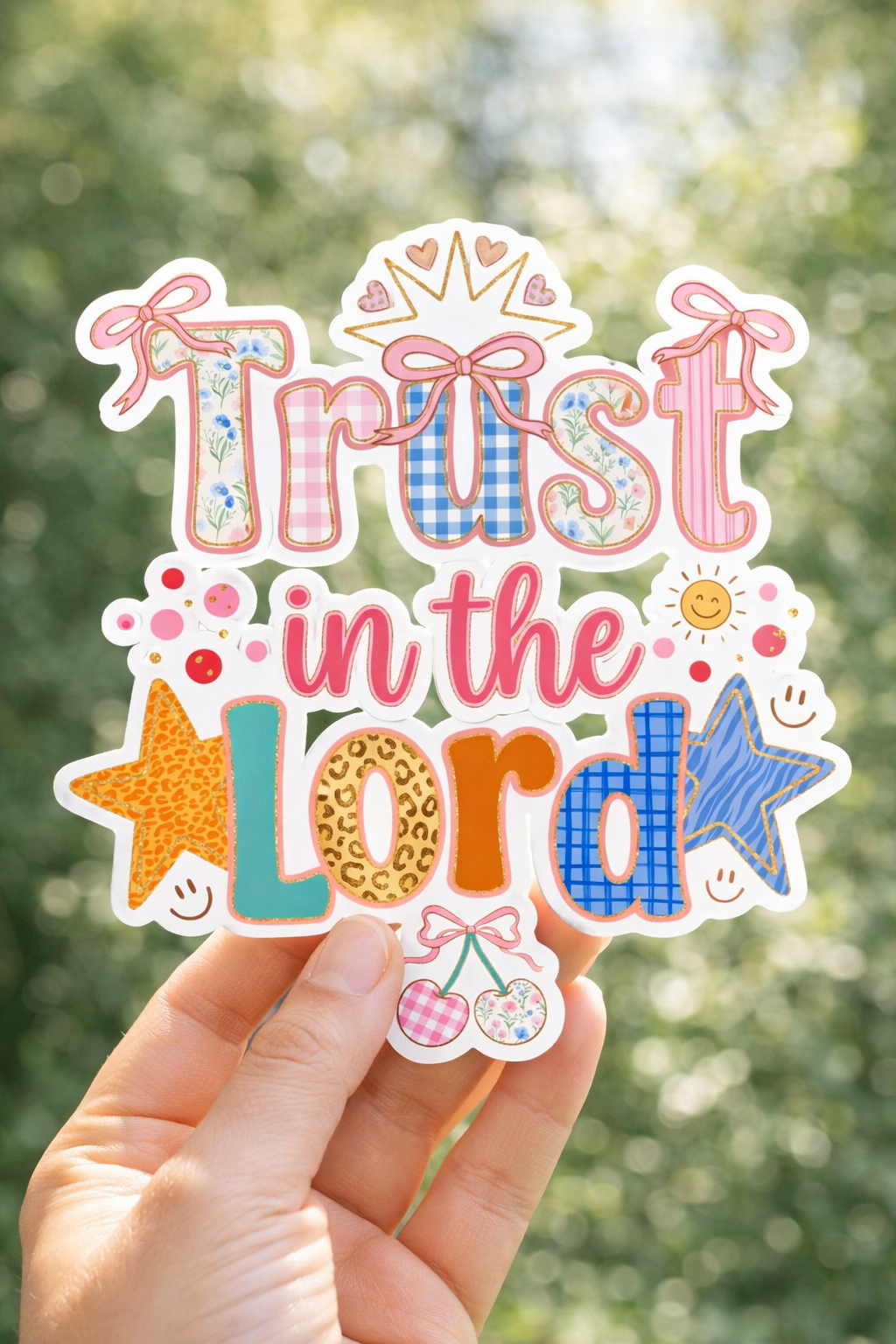 Hand holding a colorful 'Trust in the Lord' sticker against a blurred green background