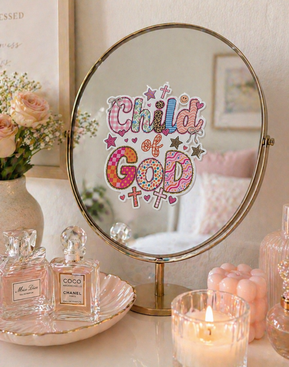 Child of God Christian sticker on a vanity mirror with pink aesthetic decor, perfume bottles, candlelight, and soft feminine bedroom styling.