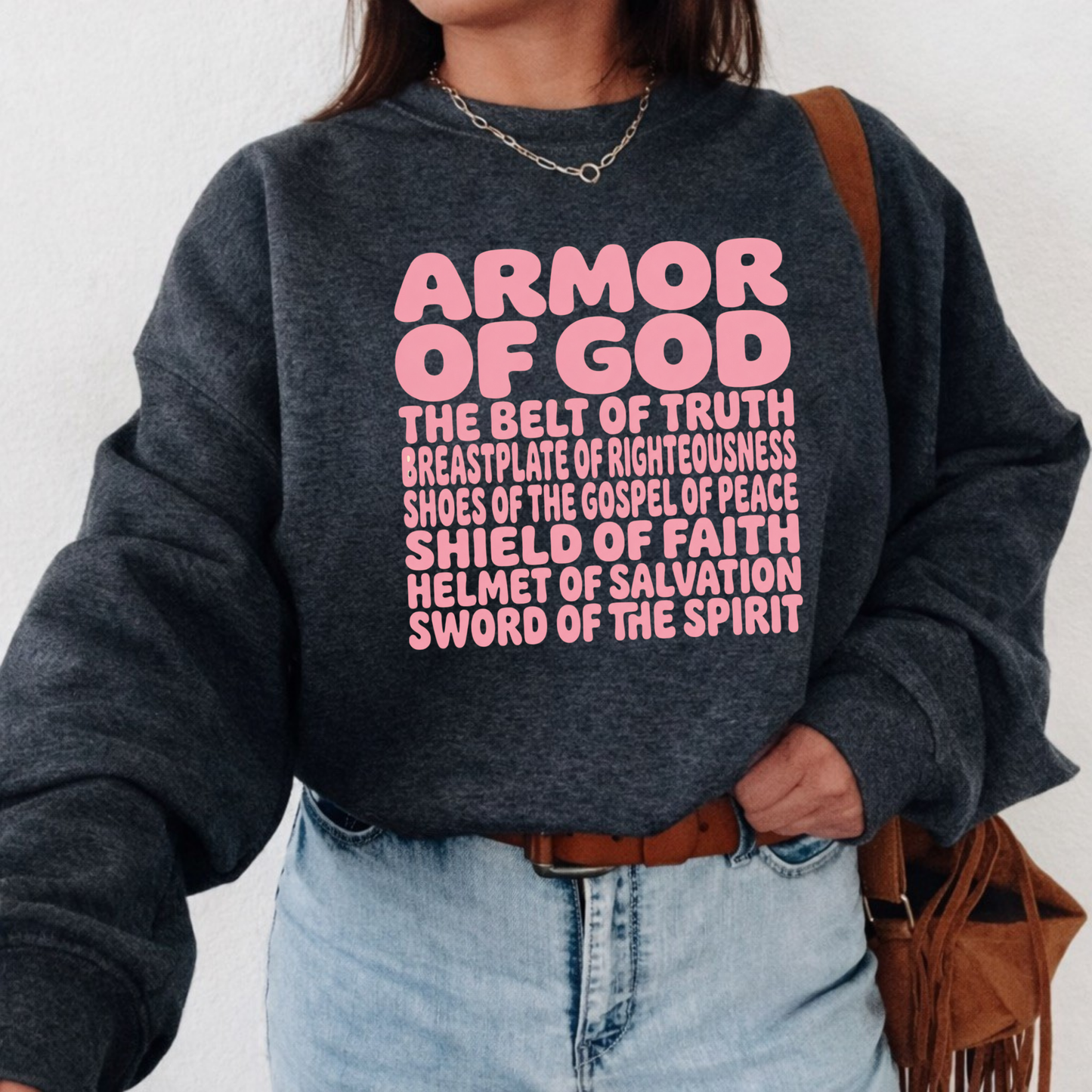 Person wearing a dark gray sweatshirt with pink 'Armor of God' text on a white background