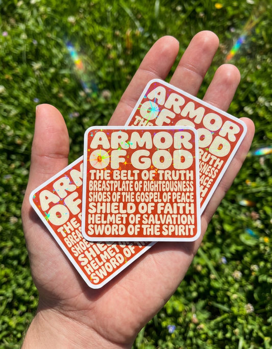 Two 'Armor of God' stickers held in a hand with a grassy background