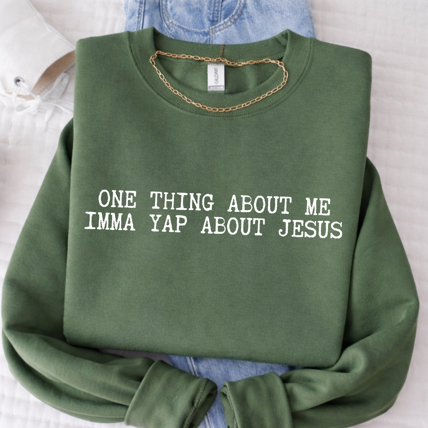 Green sweatshirt with text 'ONE THING ABOUT ME IMMA YAP ABOUT JESUS' on a light background