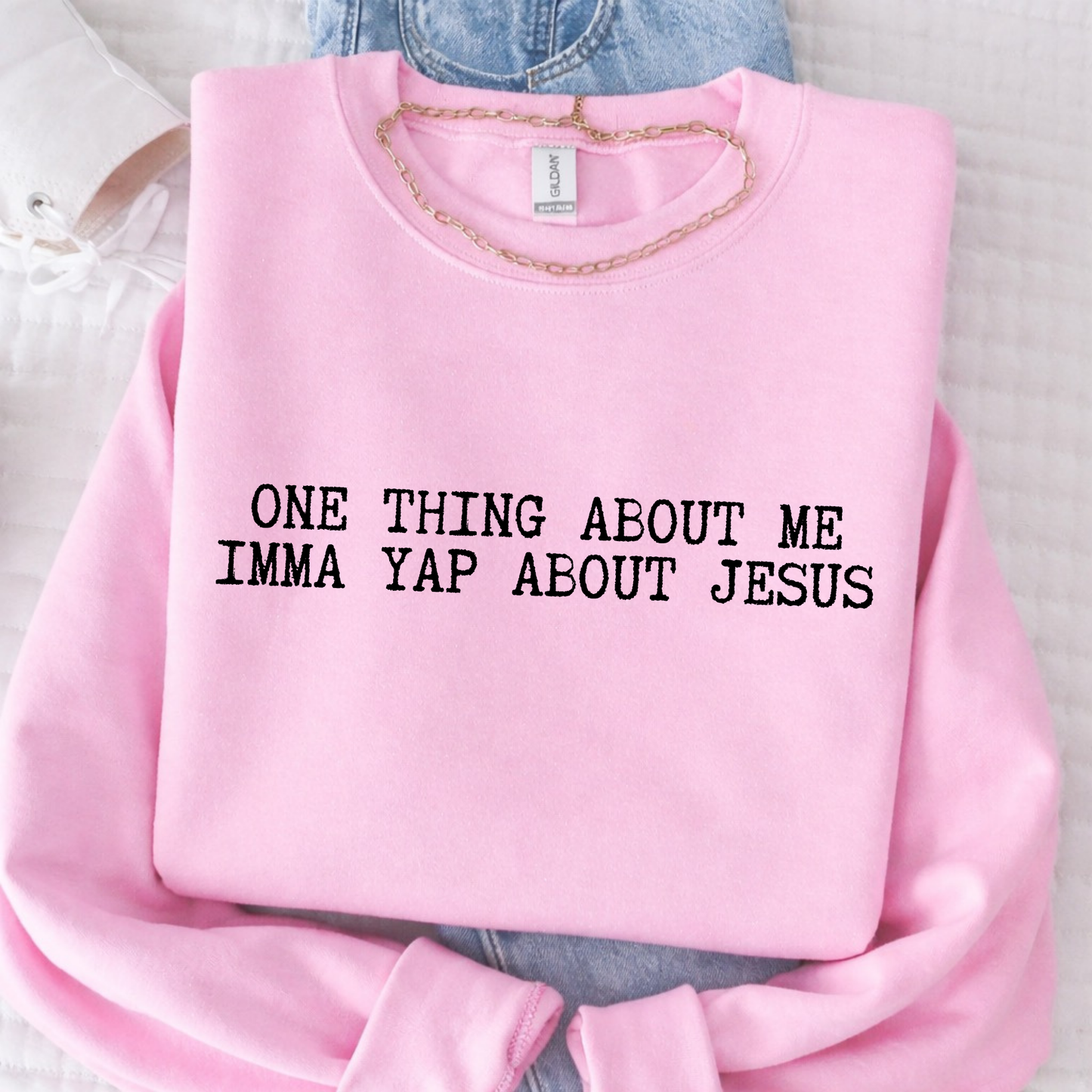 Pink sweatshirt with text 'ONE THING ABOUT ME IMMA YAP ABOUT JESUS' on a light background