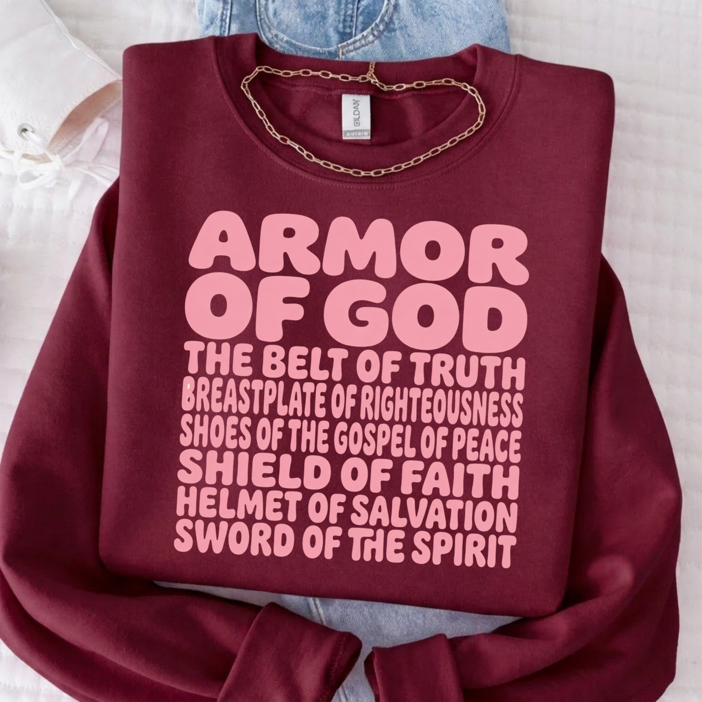 Person wearing a maroon sweatshirt with 'Armor of God' text on a white background
