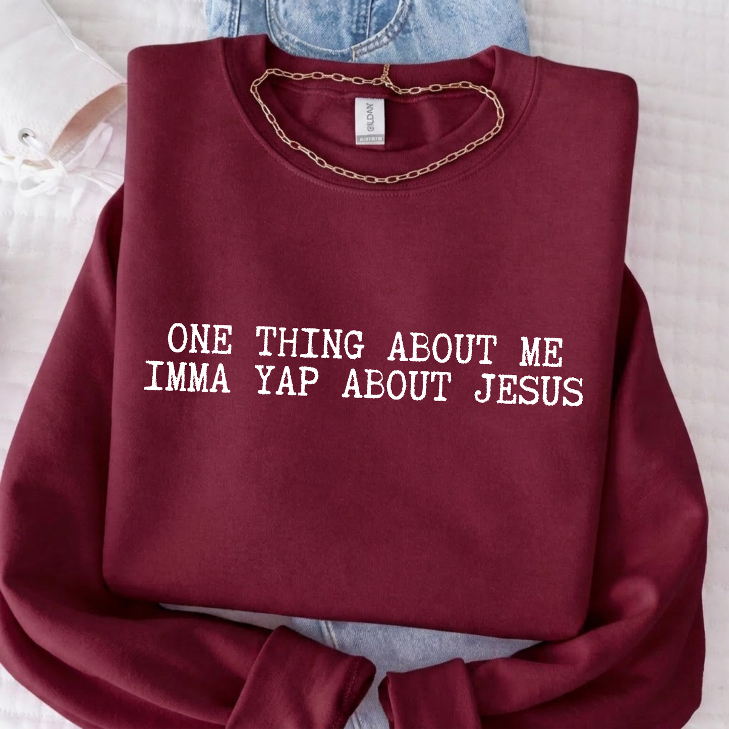 Maroon sweatshirt with text 'ONE THING ABOUT ME IMMA YAP ABOUT JESUS' on a light background