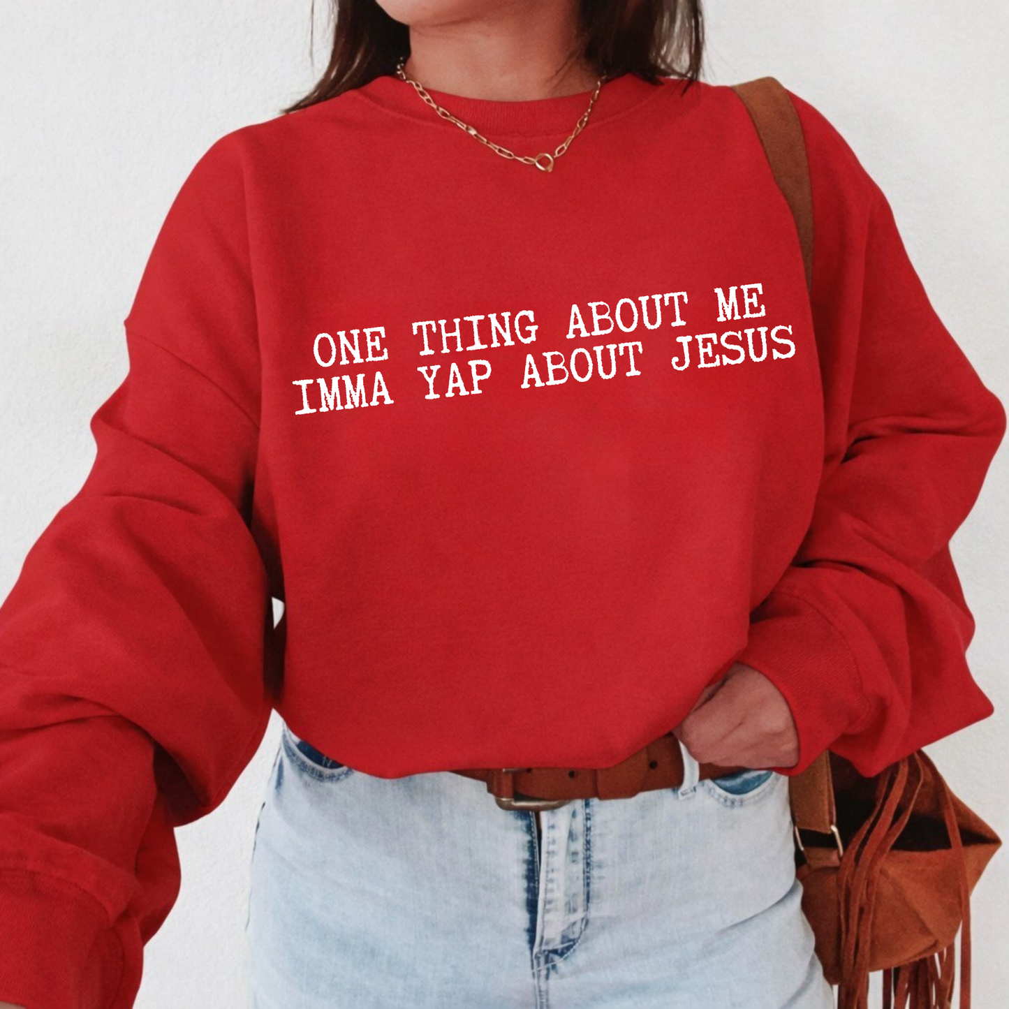 Person wearing a red sweatshirt with text 'ONE THING ABOUT ME IMMA YAP ABOUT JESUS', standing against a plain background